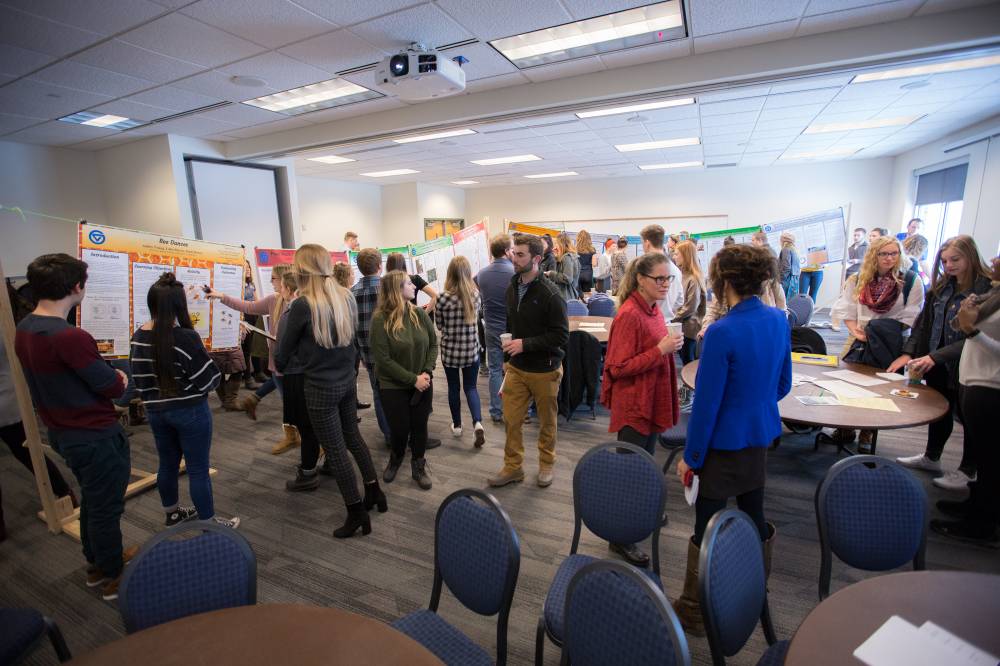 Attendees chat while viewing students' poster presentations.